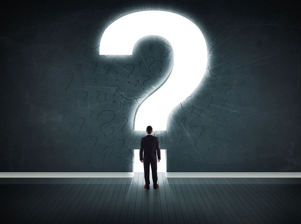 Business man looking at wall with a bright question mark concept.jpeg Business man looking at wall with a bright question mark concept.jpeg